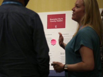 Woman gesturing in front of a poster at conference