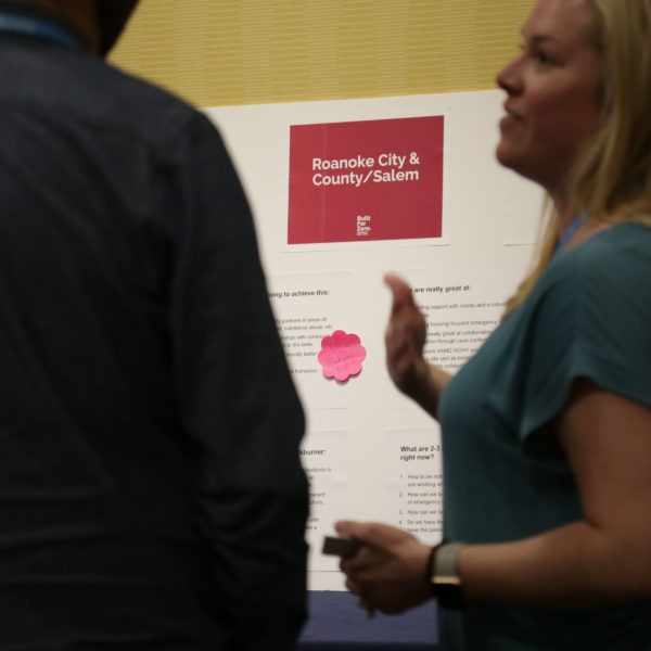 Woman gesturing in front of a poster at conference