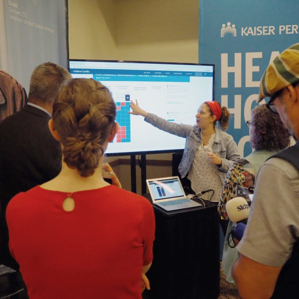 Person pointing to graph on screen in front of small crowd