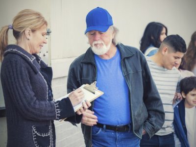 Woman with clipboard talking with older man in line