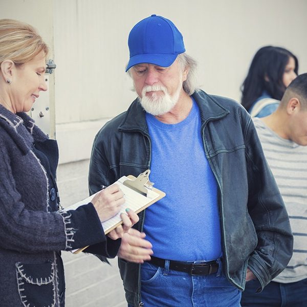Woman with clipboard talking with older man in line