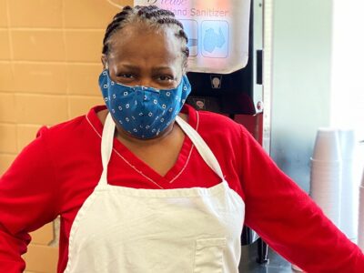 Woman in face mask and apron in kitchen